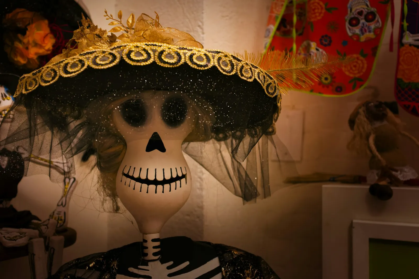 A skeleton figure dressed as a Catrina, with a wide hat and a veil, flowers at the brim