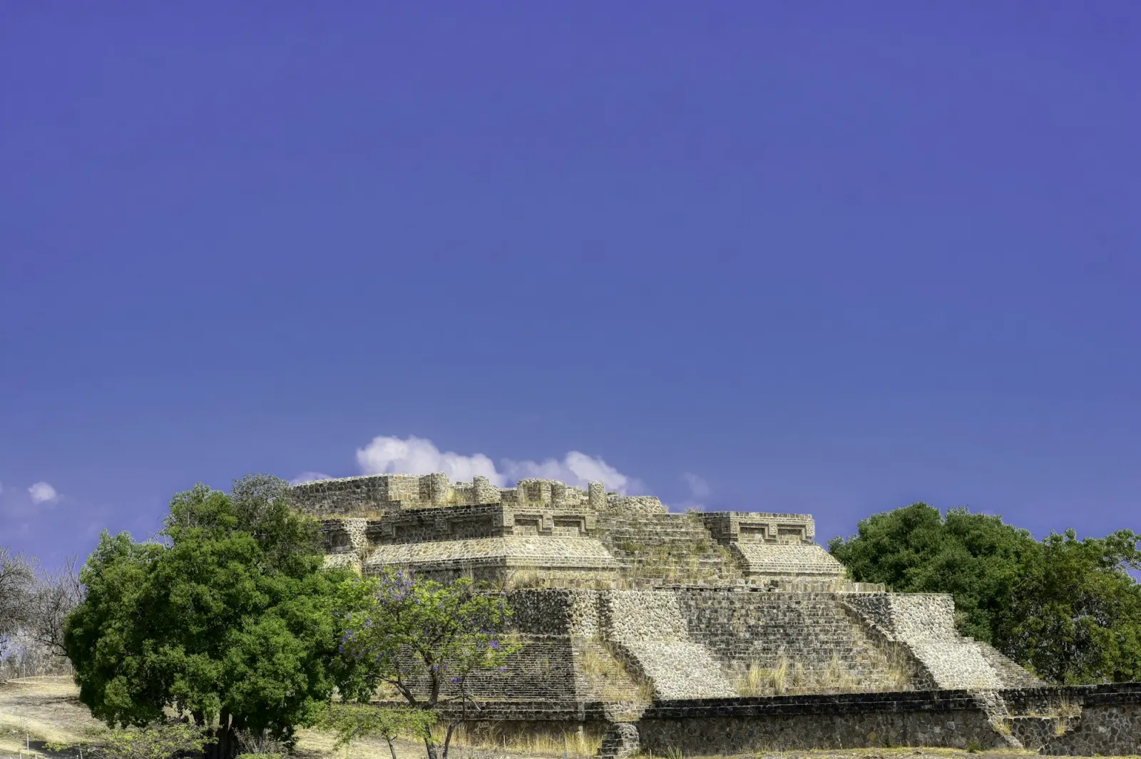 The stone platforms and pyramids of Monte Albán on a flat hilltop, hills in the distance