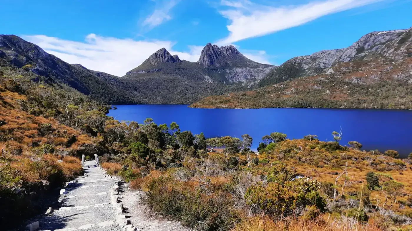 A boardwalk leading to Dove Lake with Cradle Mountain rising behind it under a clear sky