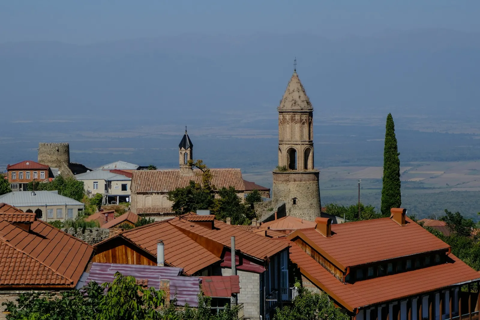 Sighnaghi's terracotta roofs and a church bell tower on a hillside, the valley far below